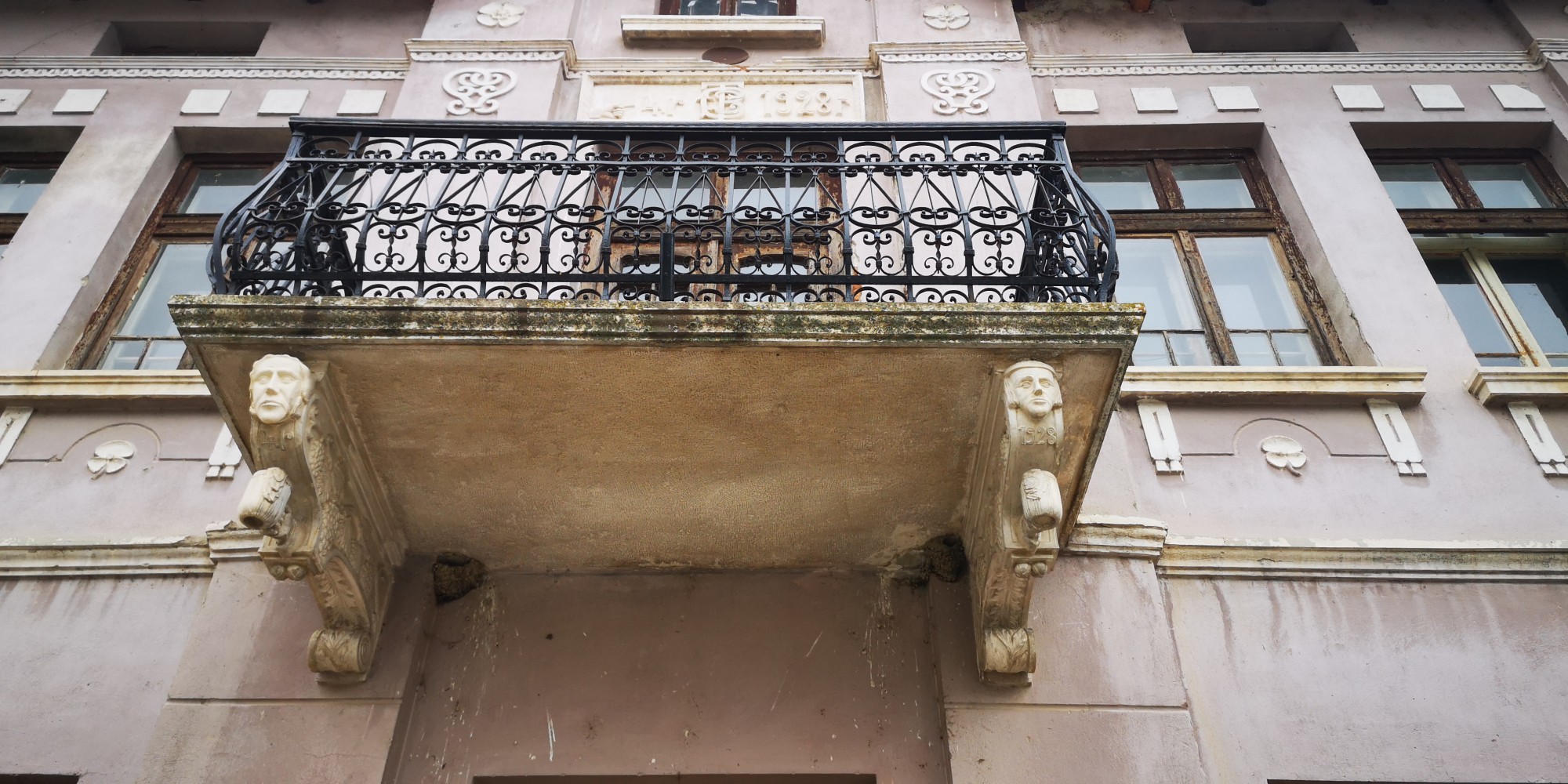 Balcony and decorative facade details of a historic house, with metal railing and architectural ornaments.